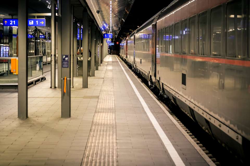 Vienna railway station guides for blind people on the ground with a train on the right.